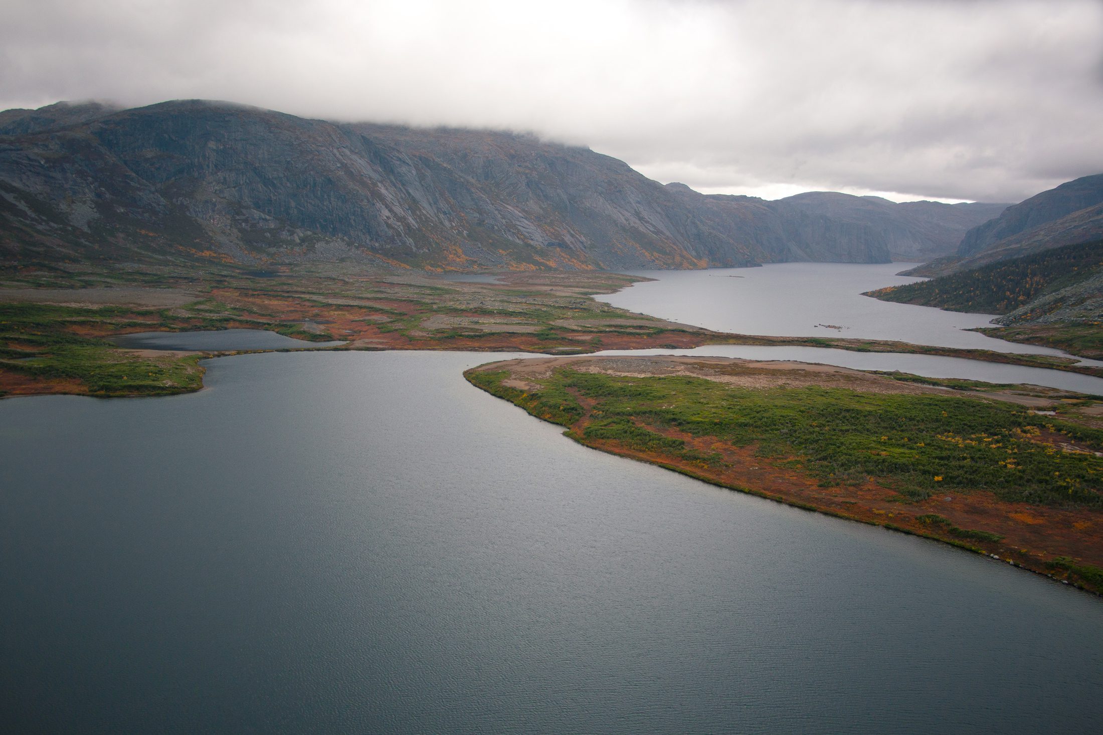 An elevated vista of Memekueshu lake in Akamiu-Uapishku, with a mountain range in the distance